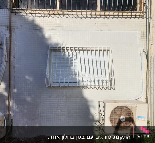 חלון עם סורגים לבנים על קיר חיצוני